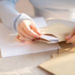 封筒に書類を入れている手元